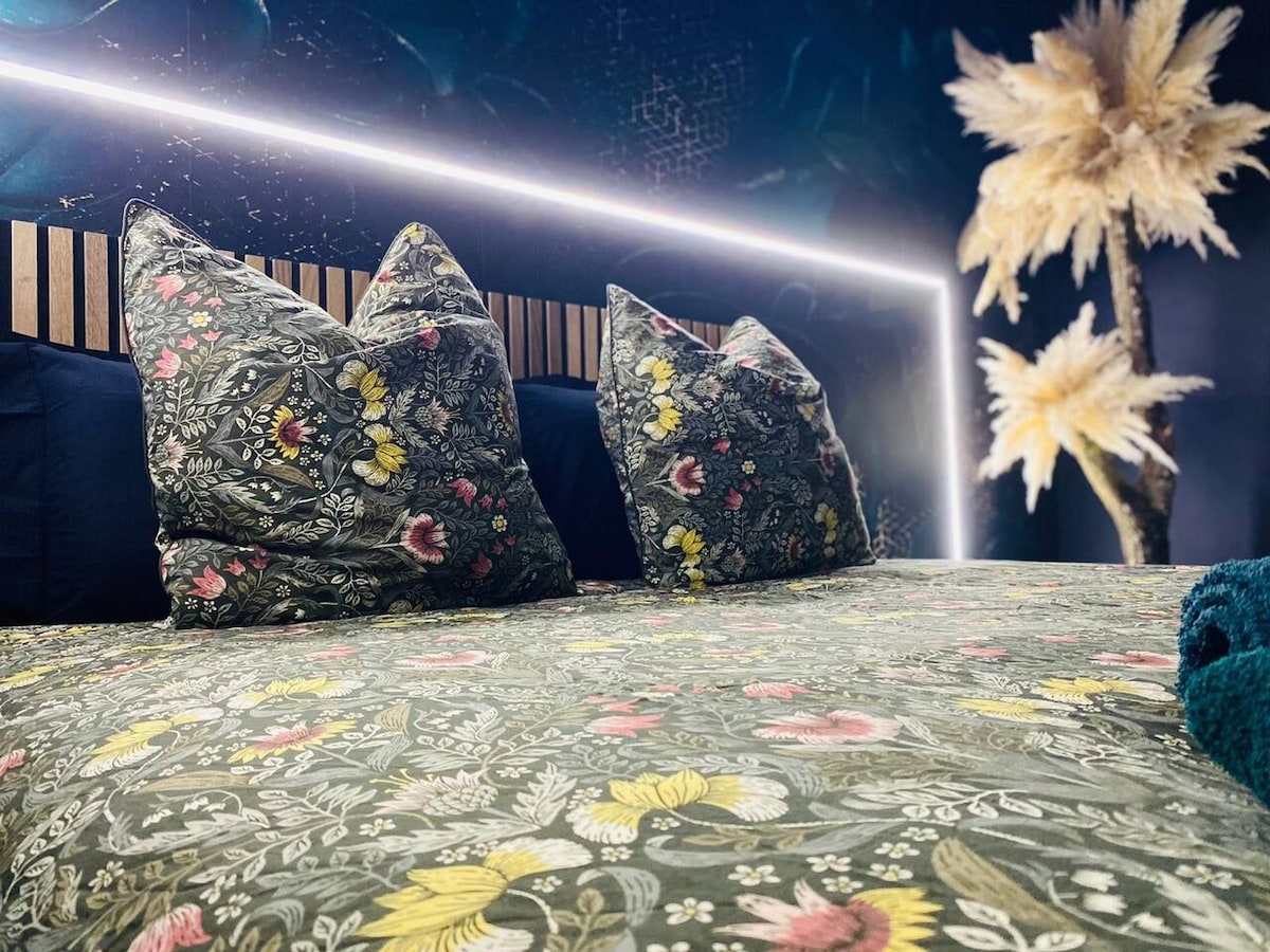 Chambre romantique avec grand lit Queen-size, couette florale et encadrement LED